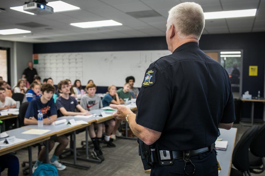 A uniformed officer talks with a classroom of teenagers